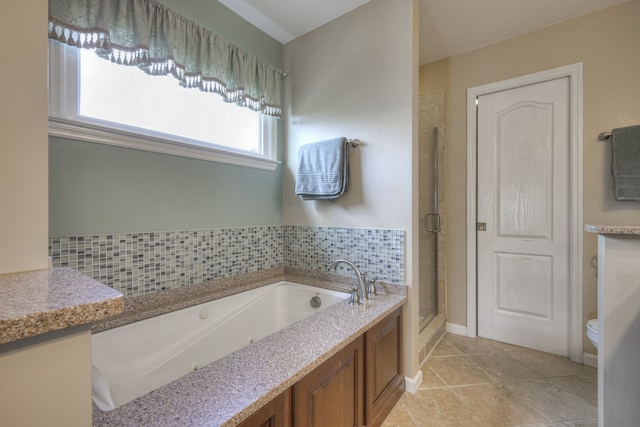 bathroom with tile patterned floors, toilet, plus walk in shower, and backsplash