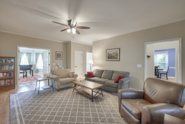 living room with light hardwood / wood-style floors, ceiling fan, and ornamental molding