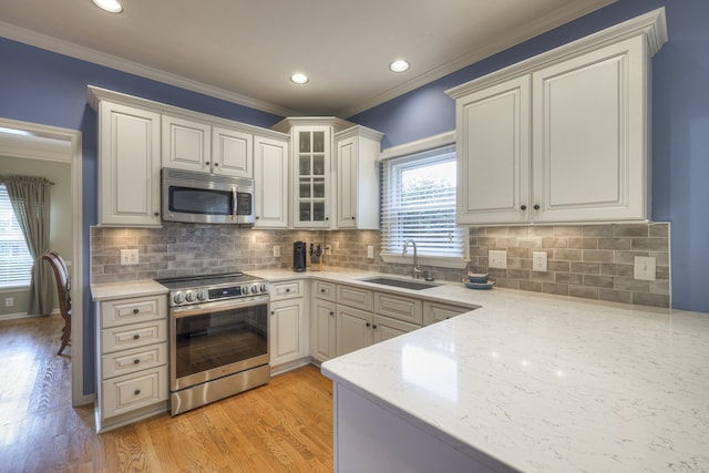 kitchen with light hardwood / wood-style floors, white cabinets, decorative backsplash, sink, and appliances with stainless steel finishes