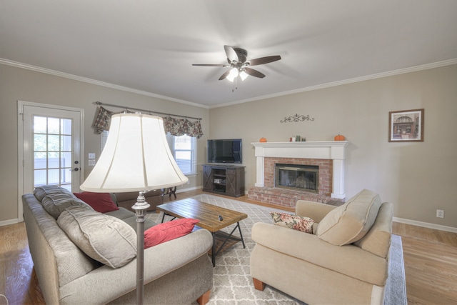 living room featuring a brick fireplace, a healthy amount of sunlight, and light wood-type flooring