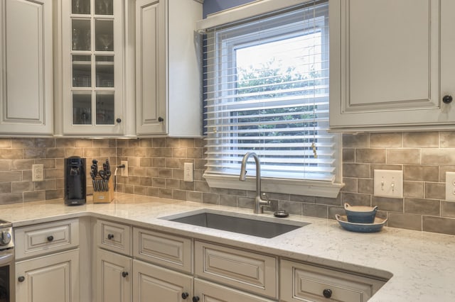 kitchen featuring light stone countertops, sink, and tasteful backsplash