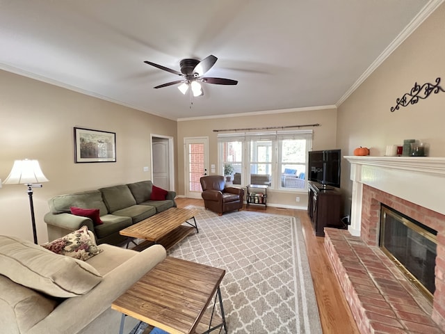 living room featuring hardwood / wood-style floors, ceiling fan, a fireplace, and crown molding