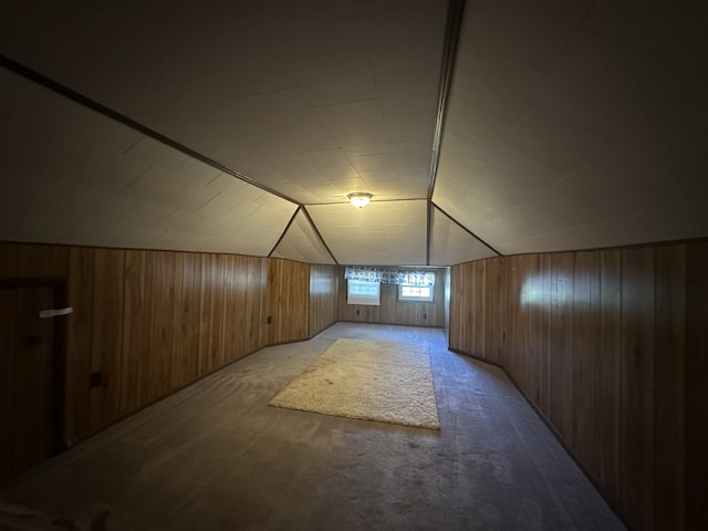 additional living space with carpet floors, wood walls, and vaulted ceiling