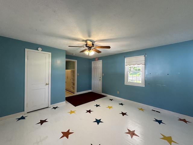 unfurnished bedroom featuring ceiling fan, a textured ceiling, and ensuite bath