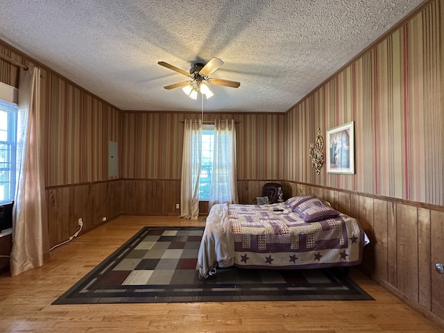 unfurnished bedroom with wood-type flooring, a textured ceiling, multiple windows, and ceiling fan