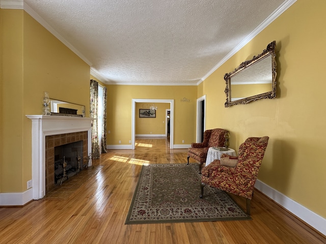 living area with light wood-type flooring, crown molding, a textured ceiling, and a tile fireplace