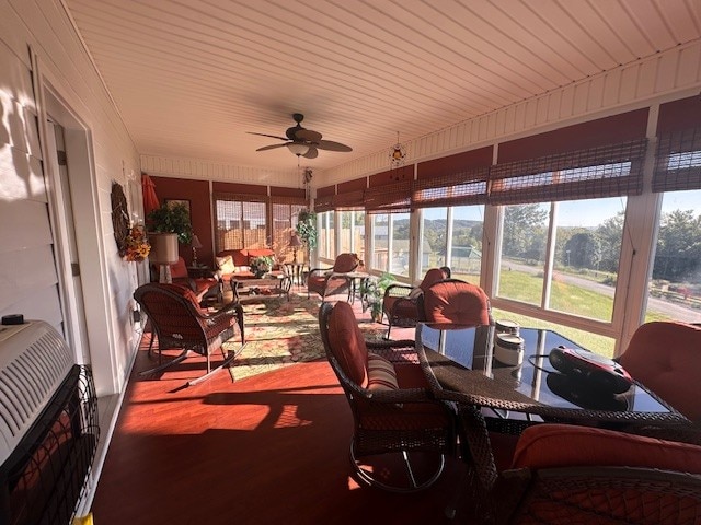 sunroom featuring a wealth of natural light, heating unit, and ceiling fan