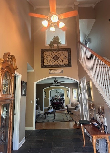 entrance foyer featuring ornamental molding, a high ceiling, dark hardwood / wood-style floors, and ceiling fan