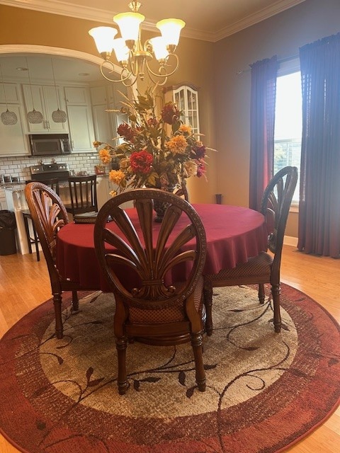 dining area featuring an inviting chandelier, light hardwood / wood-style flooring, and crown molding