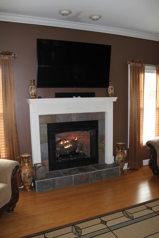 interior details with crown molding, wood-type flooring, and a tile fireplace