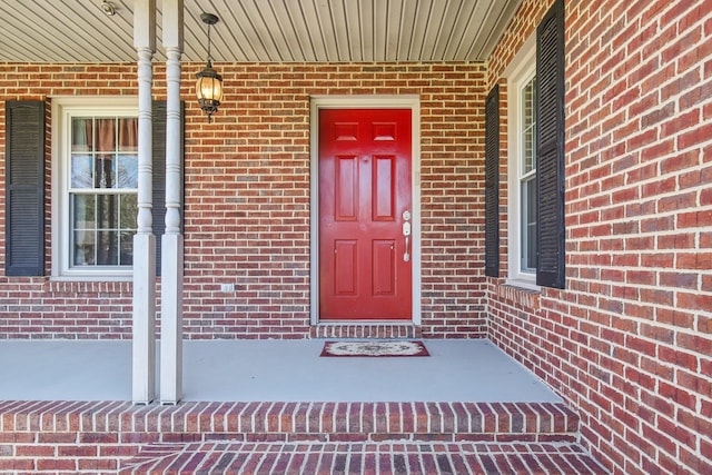 doorway to property with brick siding and a porch