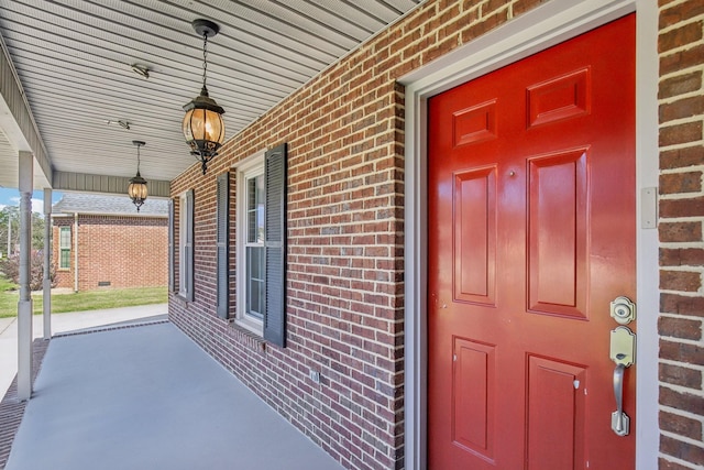 doorway to property featuring brick siding and covered porch
