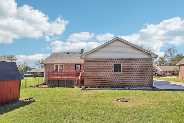 back of house with a yard, a deck, and a storage shed