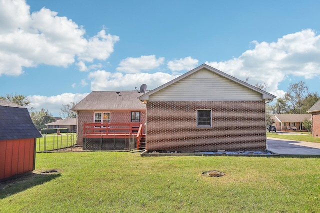 back of property with a storage shed, a yard, an outdoor structure, brick siding, and a deck