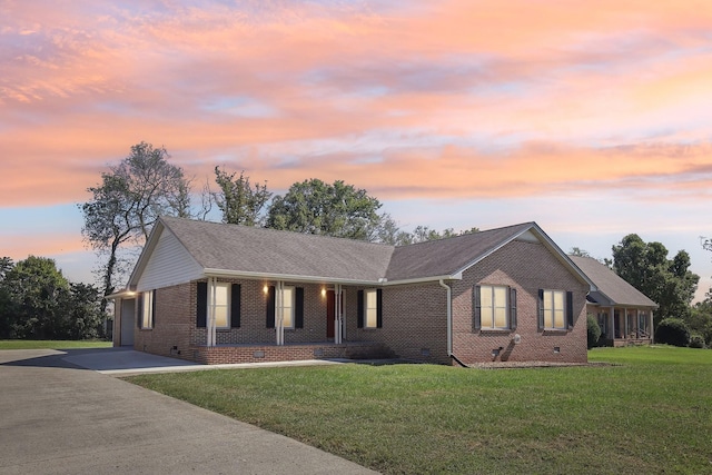 single story home featuring covered porch, a lawn, crawl space, concrete driveway, and brick siding