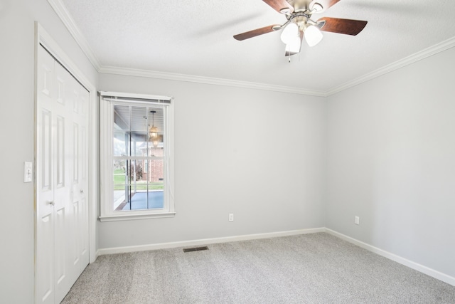 unfurnished room with ceiling fan, carpet floors, a textured ceiling, and ornamental molding