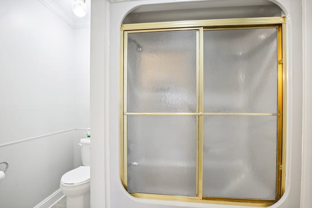 bathroom with toilet, a shower with door, and ornamental molding