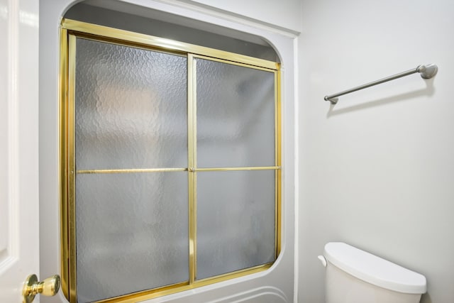 bathroom featuring enclosed tub / shower combo and toilet