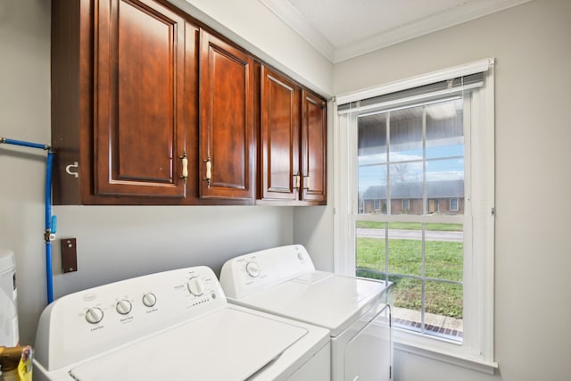 clothes washing area featuring washing machine and clothes dryer, crown molding, and cabinets