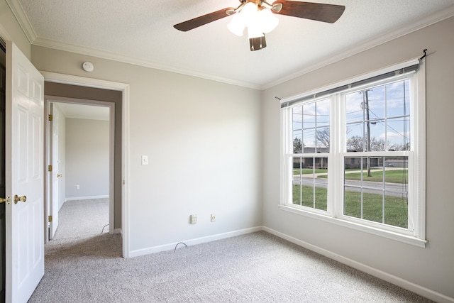 empty room featuring ceiling fan, light colored carpet, ornamental molding, and a textured ceiling