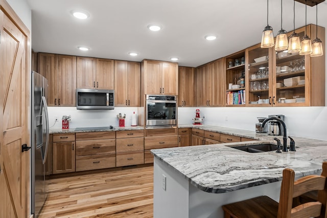 kitchen featuring a breakfast bar, sink, kitchen peninsula, hanging light fixtures, and appliances with stainless steel finishes