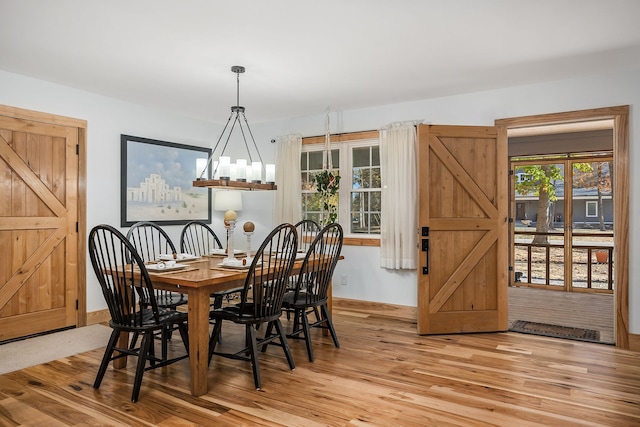 dining area with an inviting chandelier, light wood-type flooring, and a barn door