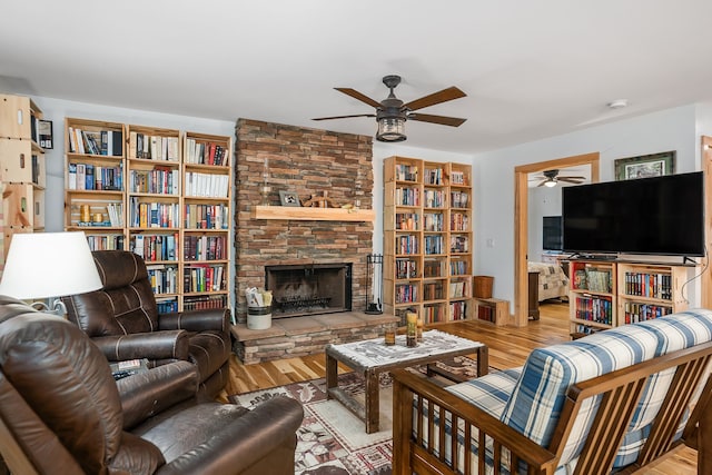 living room featuring light hardwood / wood-style flooring, ceiling fan, and a fireplace