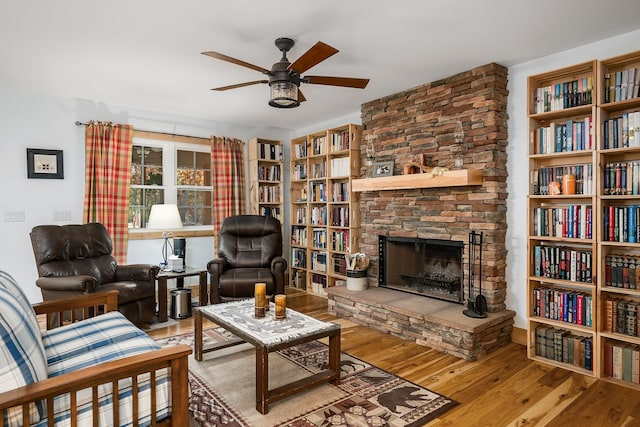 living area featuring ceiling fan, hardwood / wood-style flooring, and a fireplace