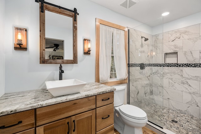 bathroom with a tile shower, a baseboard radiator, ceiling fan, vanity, and toilet