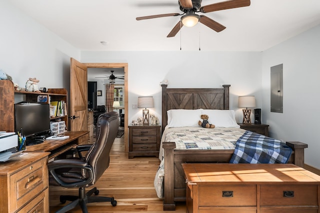 bedroom featuring ceiling fan, light hardwood / wood-style flooring, and electric panel