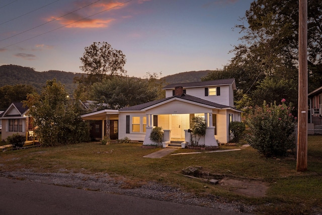 view of front of home with a mountain view, a lawn, and covered porch