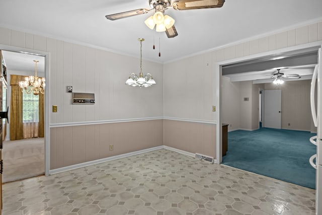 unfurnished dining area featuring carpet floors, ceiling fan with notable chandelier, wooden walls, and ornamental molding
