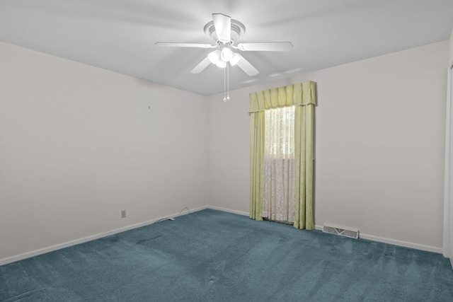 spare room featuring dark colored carpet and ceiling fan