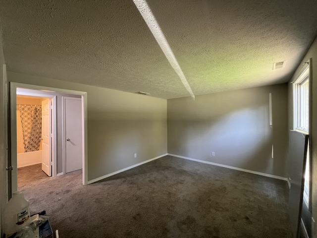 bonus room with dark carpet and a textured ceiling