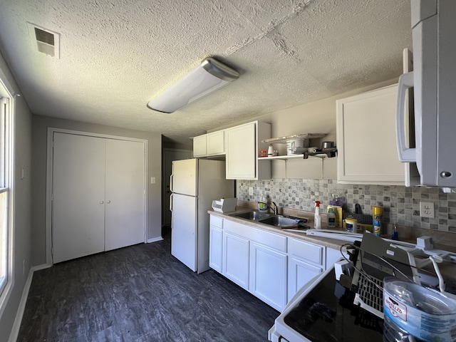 kitchen featuring white cabinets, sink, a textured ceiling, dark wood-type flooring, and decorative backsplash