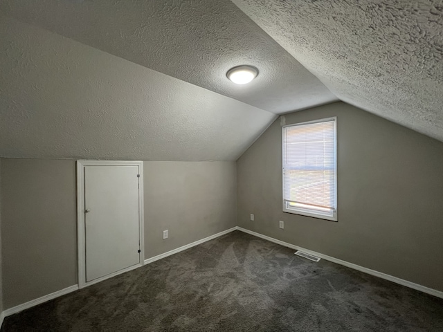 bonus room with a textured ceiling, vaulted ceiling, and dark carpet