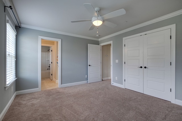 unfurnished bedroom featuring a closet, ceiling fan, ornamental molding, ensuite bath, and light colored carpet