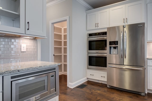 kitchen featuring decorative backsplash, white cabinets, light stone countertops, stainless steel appliances, and dark hardwood / wood-style floors