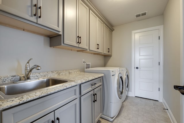 clothes washing area featuring light tile patterned floors, cabinets, sink, and washing machine and dryer