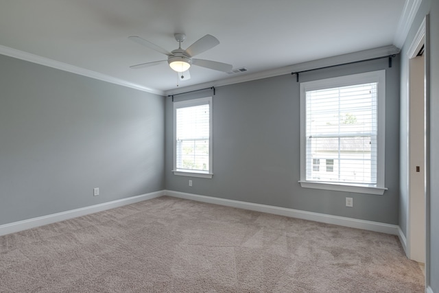 carpeted spare room with ceiling fan, plenty of natural light, and ornamental molding