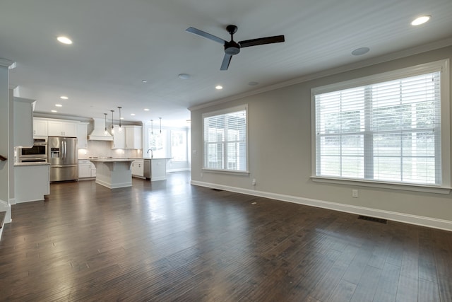 unfurnished living room with ceiling fan, dark hardwood / wood-style floors, and crown molding