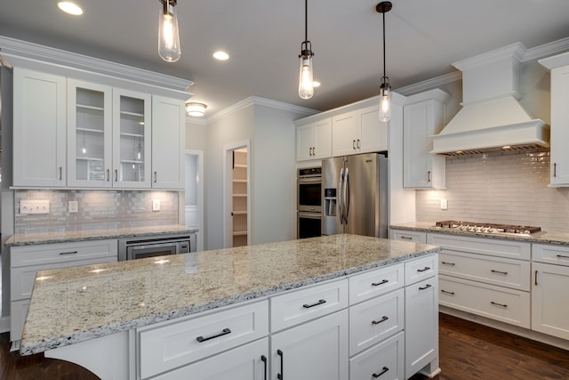 kitchen with stainless steel appliances, white cabinets, and premium range hood