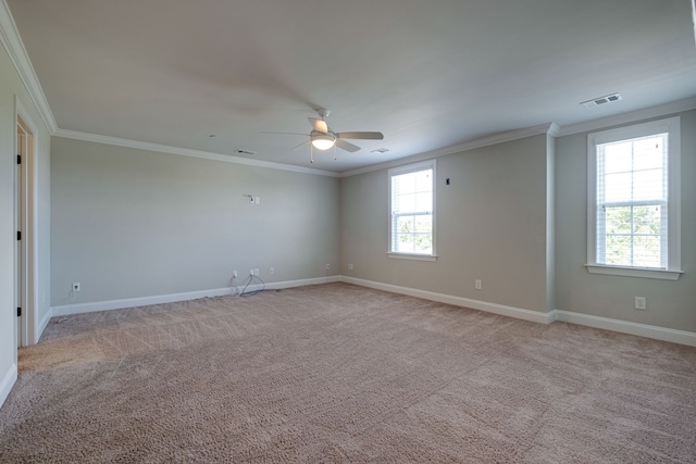 carpeted spare room with ceiling fan, ornamental molding, and a wealth of natural light