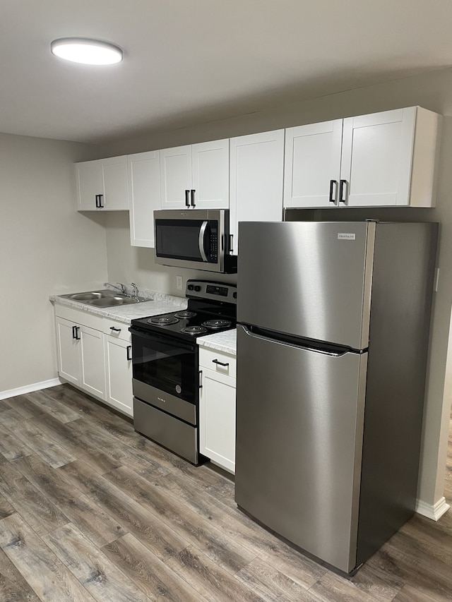 kitchen featuring appliances with stainless steel finishes, sink, dark hardwood / wood-style flooring, and white cabinets