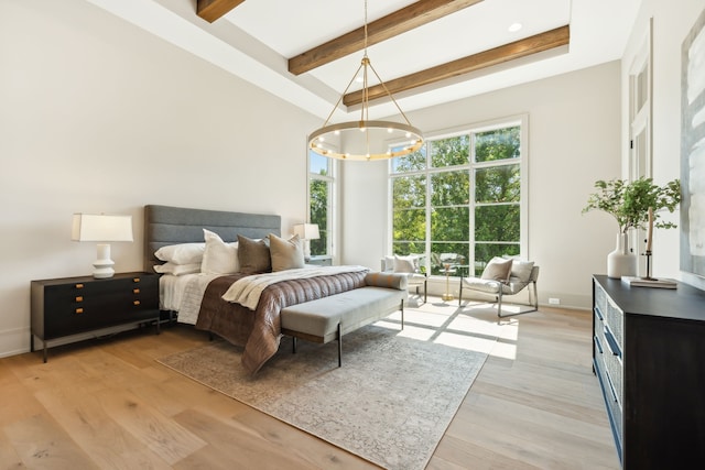 bedroom with beam ceiling, light hardwood / wood-style floors, an inviting chandelier, and a raised ceiling