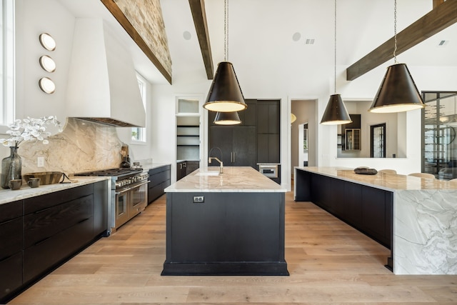 kitchen featuring a large island, a high ceiling, beamed ceiling, range with two ovens, and decorative light fixtures