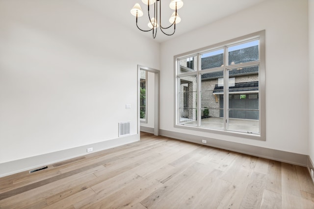 unfurnished room featuring light hardwood / wood-style flooring and a notable chandelier