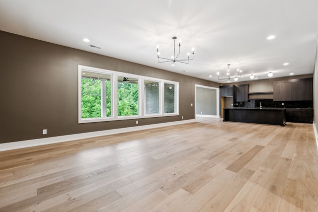 unfurnished living room with light hardwood / wood-style flooring and an inviting chandelier