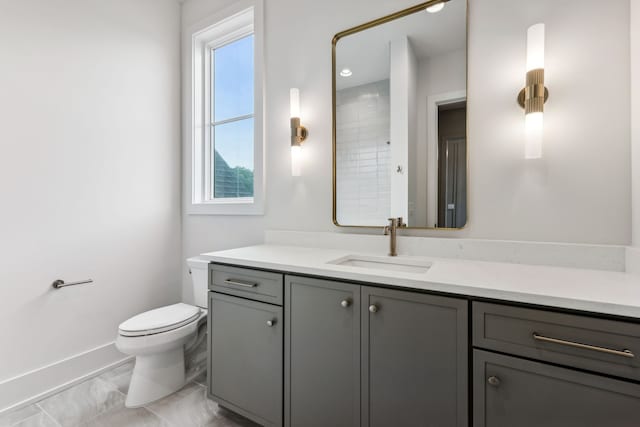 bathroom featuring vanity, a healthy amount of sunlight, and toilet