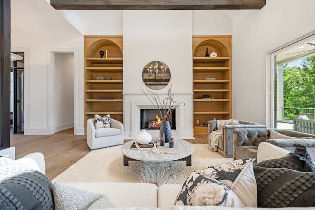 living room with wood-type flooring, built in features, and beam ceiling